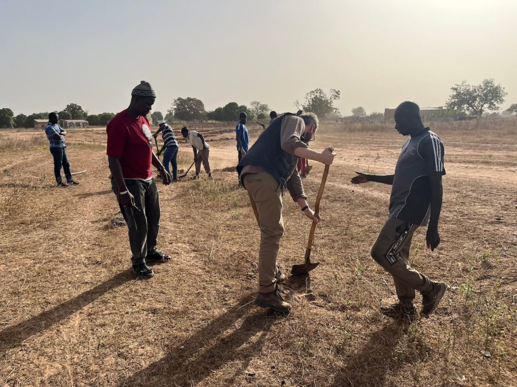 IRHA director digging during a field visit in Senegal