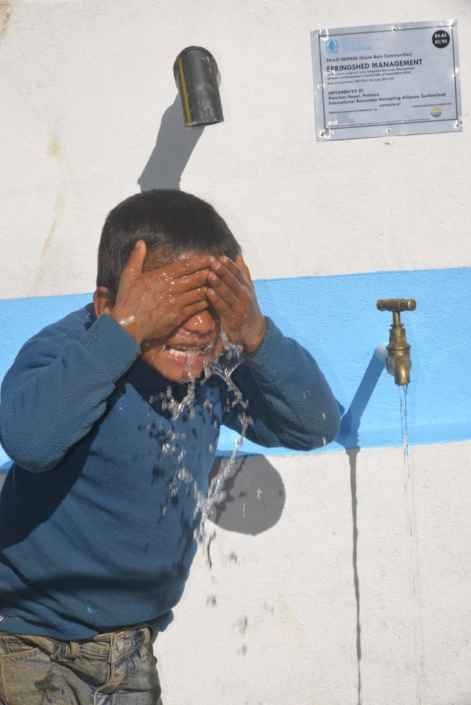 Boy washing his face with rainwater after improved access to water in Nepal
