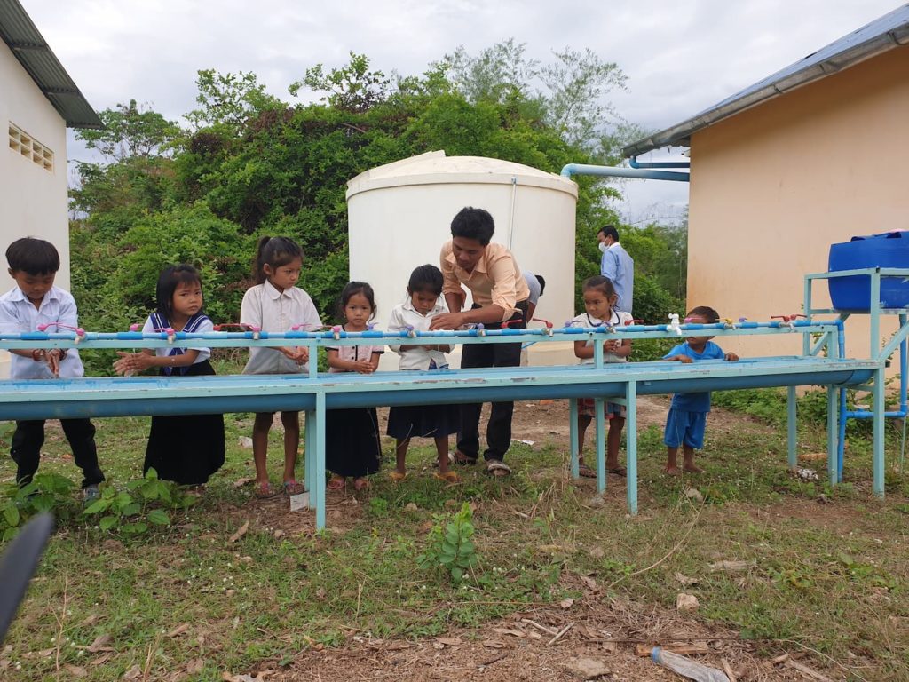 School children using a rainwater handwashing station in a blue school in Cambodia