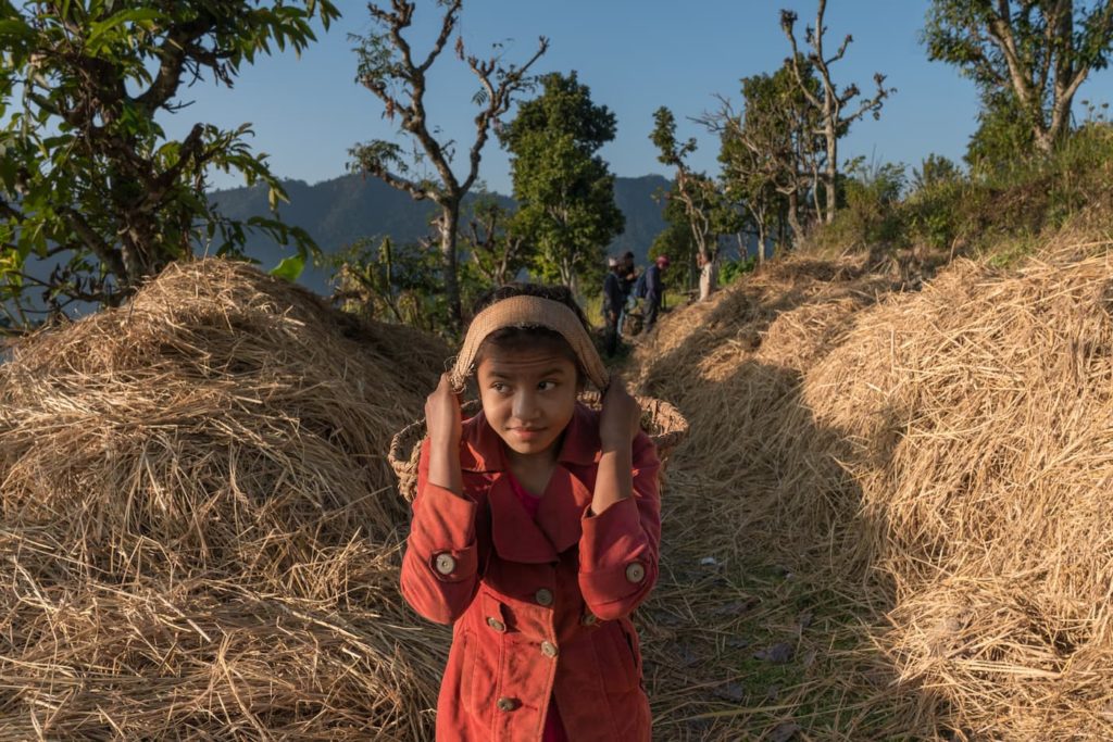 Sushmita walking with a water basket among hay bales